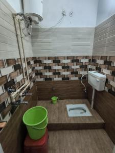 a bathroom with a toilet and a green bucket at Jai Krishna Guest House in Ayodhya