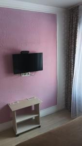 a living room with a tv on a pink wall at Гостиница"Hostel" in Karagandy