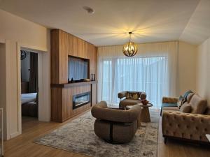 a living room with a couch and chairs and a television at Mountain Whisper Chalet in Braşov