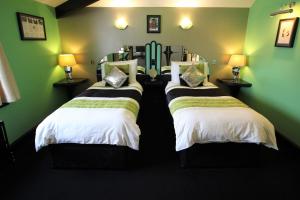 two beds in a room with green walls at The PitStop in Bishops Stortford