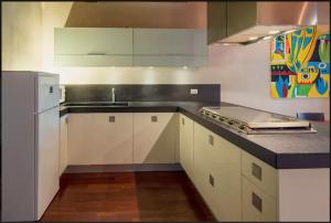 a kitchen with white cabinets and a sink and a refrigerator at Porta Vittoria Apartment in Verona