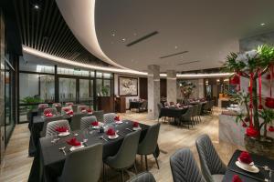 a dining room with tables and chairs and a room with windows at GrandView Hotel & Residence Hanoi in Hanoi