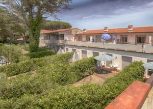 Blick auf ein Gebäude mit einer Terrasse und einem Sonnenschirm in der Unterkunft Residence Airone in Orbetello