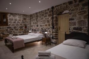 a bedroom with two beds and a stone wall at Stone Olympi Lodges - Chios Cozy Hideaways in Olýmpoi +19 photos