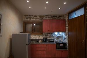 a kitchen with a white refrigerator and wooden cabinets at Stone Olympi Lodges - Chios Cozy Hideaways in Olýmpoi