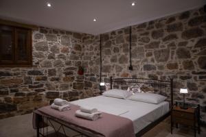 a bedroom with a bed and a stone wall at Stone Olympi Lodges - Chios Cozy Hideaways in Olýmpoi