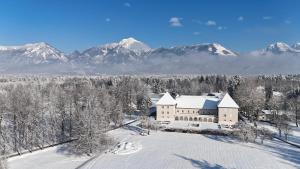 an aerial view of a building in the snow with mountains at Elegans Hotel Brdo in Kranj