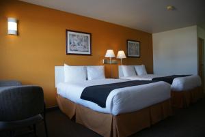 duas camas num quarto de hotel com duas cadeiras em R&R Inn & Suites em Camrose