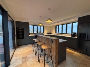 a kitchen with black cabinets and bar stools at L'Orée du Peney in Saint-Jean-dʼArvey