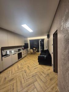 a living room with a black couch and a kitchen at Marių namai in Kaunas