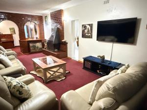 a living room with couches and a flat screen tv at Vimbainashe Villas in Umtali