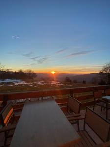 a table and chairs on a deck with the sunset at Planinski dom Kal in Dol pri Hrastniku