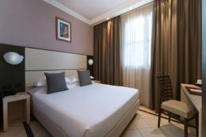 Habitación de hotel con cama blanca grande y escritorio. en CDH Hotel La Spezia, en La Spezia