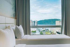 a bed in a hotel room with a large window at Cititel Express Kota Kinabalu in Kota Kinabalu