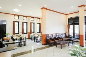 a restaurant with tables and chairs and windows at RedDoorz at Jestro Guest House Batu in Tlekung