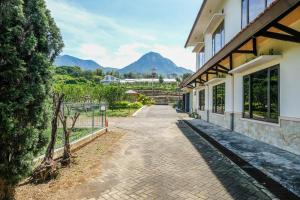 a walkway next to a building with mountains in the background at RedDoorz at Jestro Guest House Batu in Tlekung