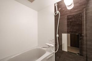 a bathroom with a tub and a shower with a mirror at Hills Niseko 105 in Niseko
