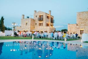a group of people sitting in chairs by a pool at Arodamos Villa with a pool, children's games, and BBQ, perfect for 23 people! in Skouloúfia