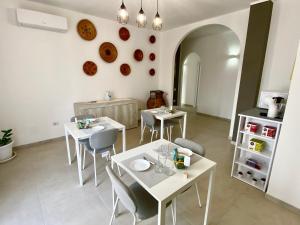 a dining room with white tables and chairs at Rooms Domu Ajo in Monserrato +16 photos