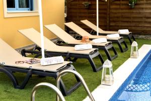 a row of lounge chairs sitting next to a swimming pool at Lindos Luxury Retro Villas in Lindos