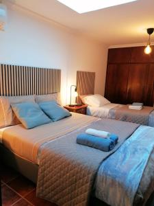 a bedroom with two beds with blue towels on them at 9, Cimo da Aldeia in Aldeia de João Pires