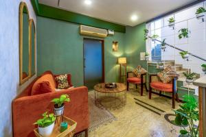 a living room with a couch and some plants at Olive Zip Rest House Road by Embassy Group in Bangalore
