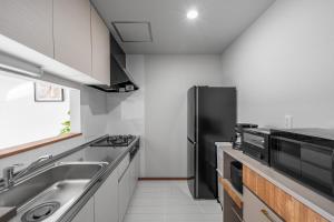 a kitchen with a sink and a black refrigerator at Hills Niseko B in Niseko