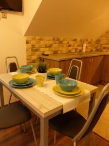 a wooden table with yellow bowls and plates on it at Apartament Pozytywka in Tenczynek