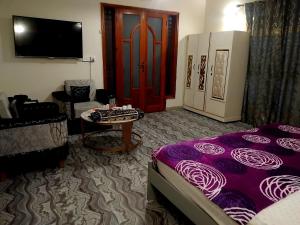 a room with a bed and a table and a tv at Hotel Royal Inn in Karachi