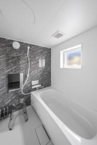 a white bathroom with a tub and a tv at Hills Niseko B in Niseko