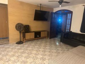 a living room with a fan and a flat screen tv at Refúgio ao mar in Rio das Ostras