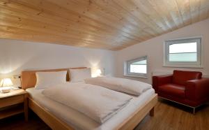 a bedroom with a bed and a red chair at Gasthof Appartement`s Staffnerhof in Kössen