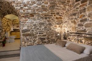 a bedroom with a stone wall with a bed at Vlychos Olympi Lodges - Chios Cozy Getaways in Olýmpoi