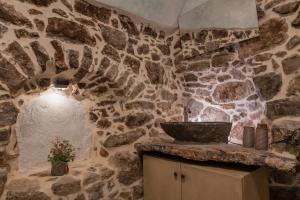 a stone bathroom with a sink and a stone wall at Vlychos Olympi Lodges - Chios Cozy Getaways in Olýmpoi +28 photos
