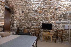 a bedroom with a stone wall with a bed and a tv at Vlychos Olympi Lodges - Chios Cozy Getaways in Olýmpoi