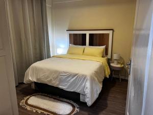 a small bedroom with a bed with yellow sheets and pillows at 6ALouieVille in Lusaka