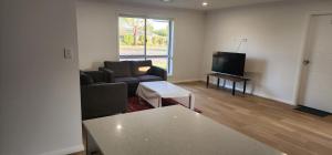 a living room with a couch and a tv at Room In Dubbo With Queens Beds in Dubbo