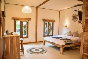 a bedroom with a bed and a desk and windows at Beda gaya ecolodge Rangsot 1 in Tanjung