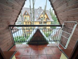 a balcony with a gate and a house in the background at VisitZakopane - Olymp Apartament in Zakopane