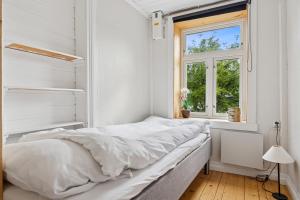 a white bedroom with a bed and a window at Brygge Sjøgata in Mosjøen