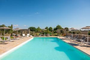 a large swimming pool with chairs and umbrellas at Agriturismo Residenza Gemma in Porto Cesareo