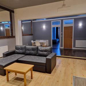 a living room with a black leather couch and a table at The Dorchester Hotel & serviced apartments FREE PARKING in Hull