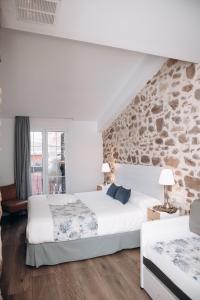 a bedroom with two beds and a stone wall at Soléa House Hotel Boutique in Benicàssim