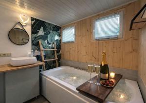 a bathroom with a tub with a bottle of champagne and glasses at Meuse Cottage in Hastière-par-delà