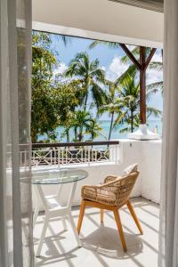 a balcony with a glass table and chairs and palm trees at Casuarina Resort and Spa in Trou aux Biches