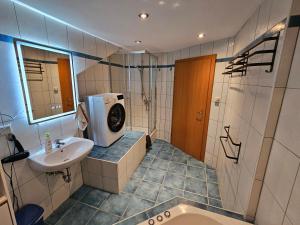 a bathroom with a sink and a washing machine at Ferienwohnung Bergherz in Sankt Johann im Walde +33 photos
