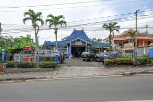 a building with a blue roof and palm trees at RedDoorz near Jawa Timur Park 1 in Batu