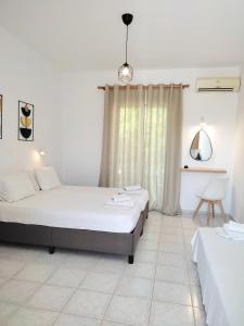 a white room with two beds and a desk at Panagiotis Studios 2 in Laganas +6 photos
