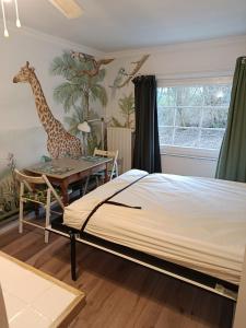 a bedroom with a bed and a table and a giraffe mural at Studio le Memagne WiFi gratuit in Lacuisine