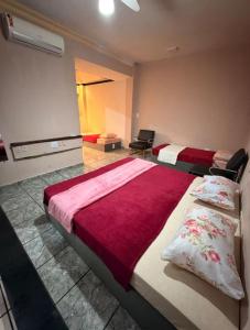 a bedroom with two beds with a red blanket at Hostel Sideral in Campo Grande